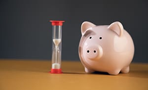 Piggy bank next to a sand hourglass