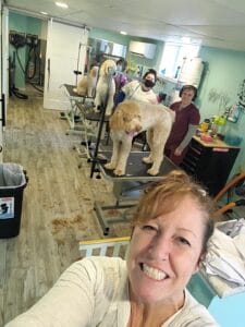 Woman holding camera with groomers and dogs in the background.