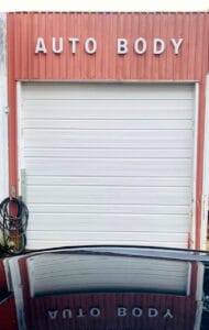 Autobody garage door with sign reflected in car hood